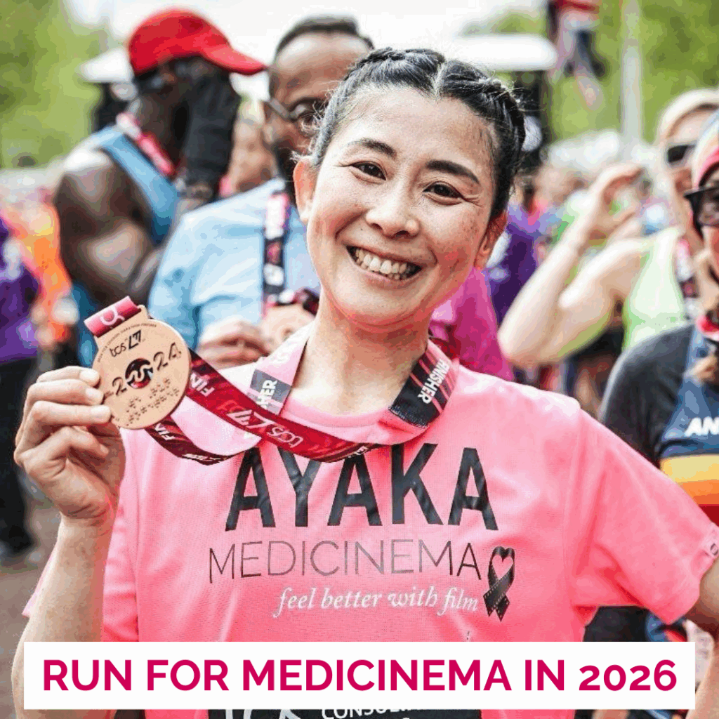 Lady in pink running jersey smiles into camera holding up her London Marathon medal